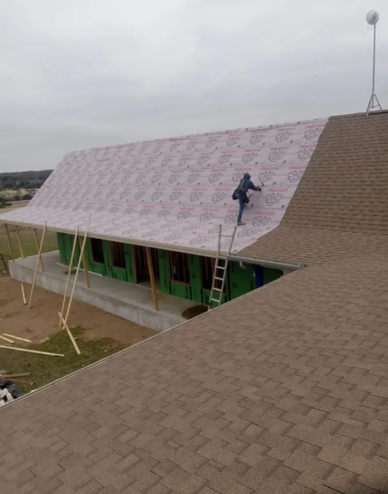 Worker preparing underlayment for a metal roof installation in Half Moon